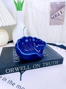 Dettaglio portasapone in ceramica blu scuro a forma di conchiglia su sfondo minimalista