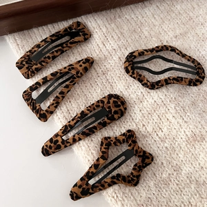 Detail of leopard print hair clips set on beige knit fabric background for warm winter style