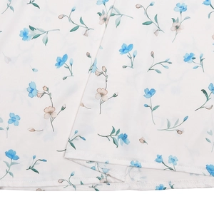 Close-up of white fabric detail with delicate blue and beige floral patterns and texture