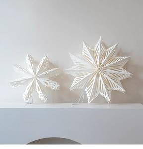 Detail of white 3D paper snowflake and star ornaments with hollow patterns and Nordic design