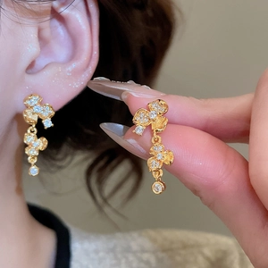 Detail showing high-shine 24K gold plated flower earrings with sparkling zircon inlay