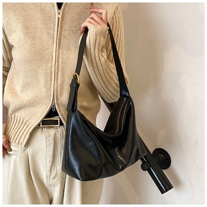 Detailed shot of black oily faux leather shoulder bag with gold metal buckle