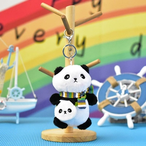 Panda plush keychain with striped scarf and mini panda backpack on wooden stand