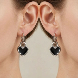 Macro detail of silver heart-shaped lock earrings with black enamel inlay on ears