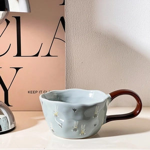 Detail of blue ceramic mug with wavy rim and cute rabbit prints for cozy tea time