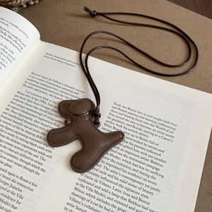Détail d'un collier pendentif chiot marron avec surpiqûres sur un livre ouvert