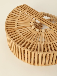 Detailed view of the hollow bamboo structure and beaded handle on a semi-circle bag