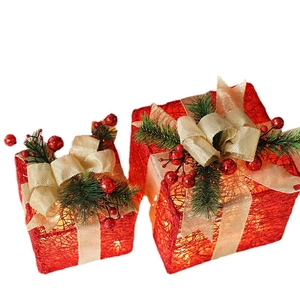 Three-piece glowing red Christmas gift boxes with gold bows and pine needle decorations