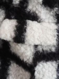 Close-up of fluffy black and white checkerboard pattern on a long wool coat