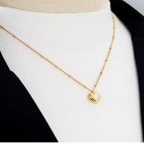 Detailed view of a gold heart necklace with white shell inlay on a model's neck