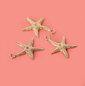 Detailed close-up of three golden starfish alloy pendants for DIY jewelry making and crafts