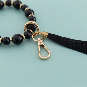 Porte-clés bracelet en perles noires avec fermoir mousqueton doré et pompon en soie