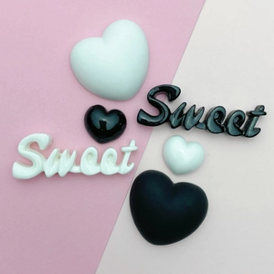Flat lay of black and white heart charms with Sweet lettering for DIY resin craft jewelry