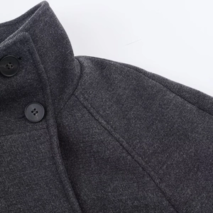 Detail view showing dark grey wool coat lapel with sharp twill weave texture and high-quality finish