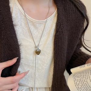 Detail of heart-shaped tiger eye stone pendant on a silver Y-shaped snake chain necklace
