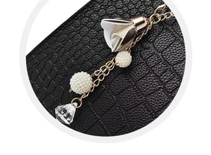 Detailed macro view of black crocodile pattern leather and gold floral chain ornament