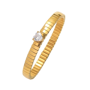 Detail of a gold flexible bracelet featuring a heart-shaped zircon on a white background