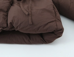 Close-up of brown padded jacket hem showing high-quality fiber texture and stitching