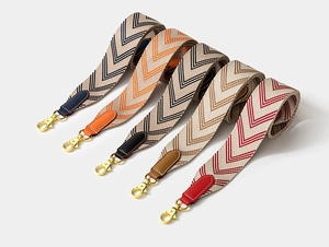 Detail of wide canvas shoulder straps with chevron pattern and leather ends