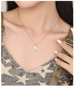 Close-up of vintage gold coin pendant necklace and matching ring on model
