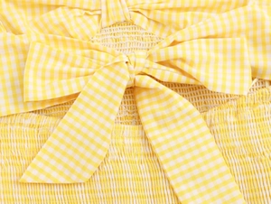 Detail of yellow gingham dress showing the bow tie and elastic pleated fabric texture
