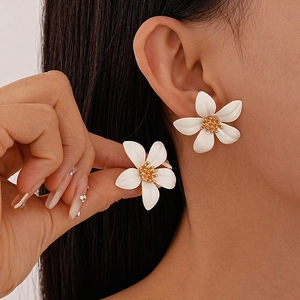 Close-up of a model wearing a white floral stud earring with a golden center accent