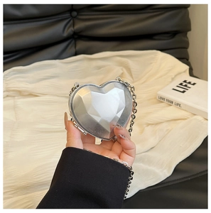 Detail of a silver heart-shaped evening bag with a metallic geometric diamond cut design
