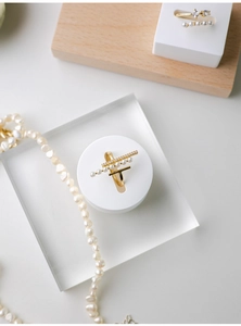 Detail of gold pearl rings with zircons on wooden stand and acrylic block