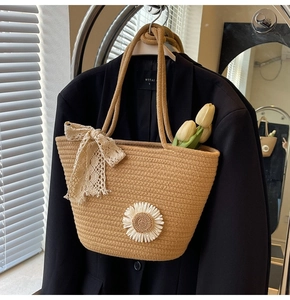 Detail of woven straw tote bag with beige lace bow and daisy flower on a blazer