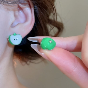 Detailed close-up of green apple stud earrings with silver stem and white enamel pulp