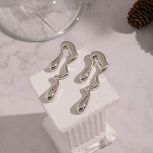 Détail de boucles d'oreilles géométriques en argent poli en forme de goutte d'eau sur socle