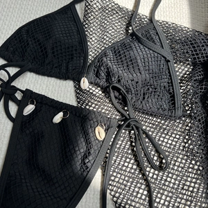 Detail of black mesh bikini set featuring hand-sewn shell charms on textured fabric