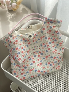 Detail of floral canvas tote bag featuring metal snap closure and pink woven handles