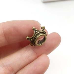Macro shot of a bronze crown alloy bead for jewelry making held between fingers