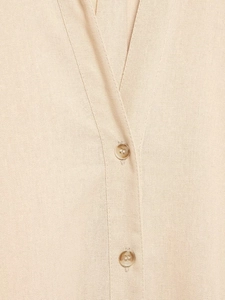 Détail de chemise beige en lin avec boutons ambrés et coutures raffinées du col en V