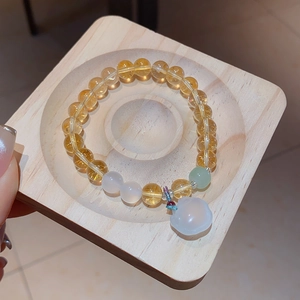 Detail of yellow crystal beaded bracelet with white chalcedony gourd pendant and green accents