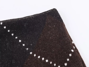 Detailed macro view of diamond pattern knitwear fabric with brown and black geometric texture