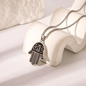 Silver stainless steel Hamsa Hand pendant necklace on a white display stand