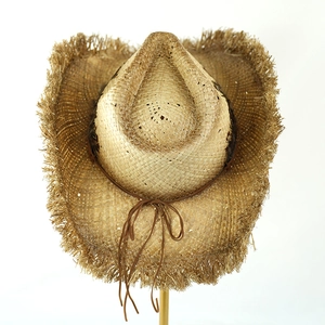Detail of hand-woven raffia cowboy hat featuring frayed edges and brown leather cord accent