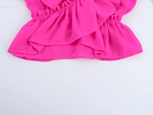 Détail du tissu en mousseline rose montrant l'ourlet à volants et la taille froncée