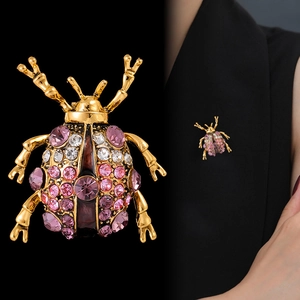 Broche insecte vintage avec strass colorés sur base dorée montrée avec style mannequin