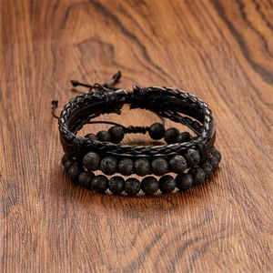 Detail of black multi-layer leather braided bracelet set with lava stones on wood surface