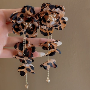 Detailed close-up of leopard print fabric flower earrings with gold tassel chains
