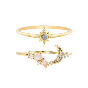 Golden star and moon ring set with blue and pink gemstones on minimalist background