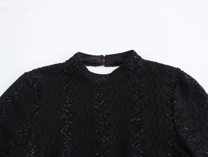 Detail of black knit dress neck with shimmery zigzag sequins and back buckle closure