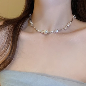 Close-up of irregular silver beads and pearl necklace worn by a model in soft lighting