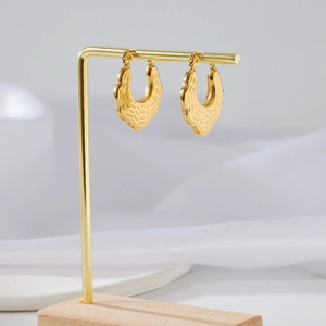 Elegant gold U-shaped earrings with textured finish on a wooden T-stand display