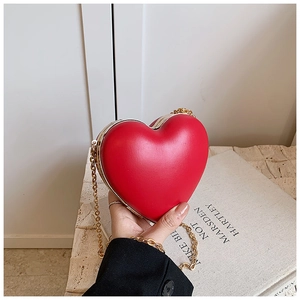 Close-up of a vibrant red heart-shaped mini crossbody bag with a sleek metal chain strap
