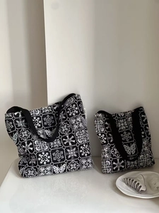 Detail of embroidered butterfly pattern on black canvas tote bag with woven straps
