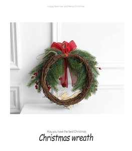 Christmas wreath detail with red bow, berries and deer pendant on white wall